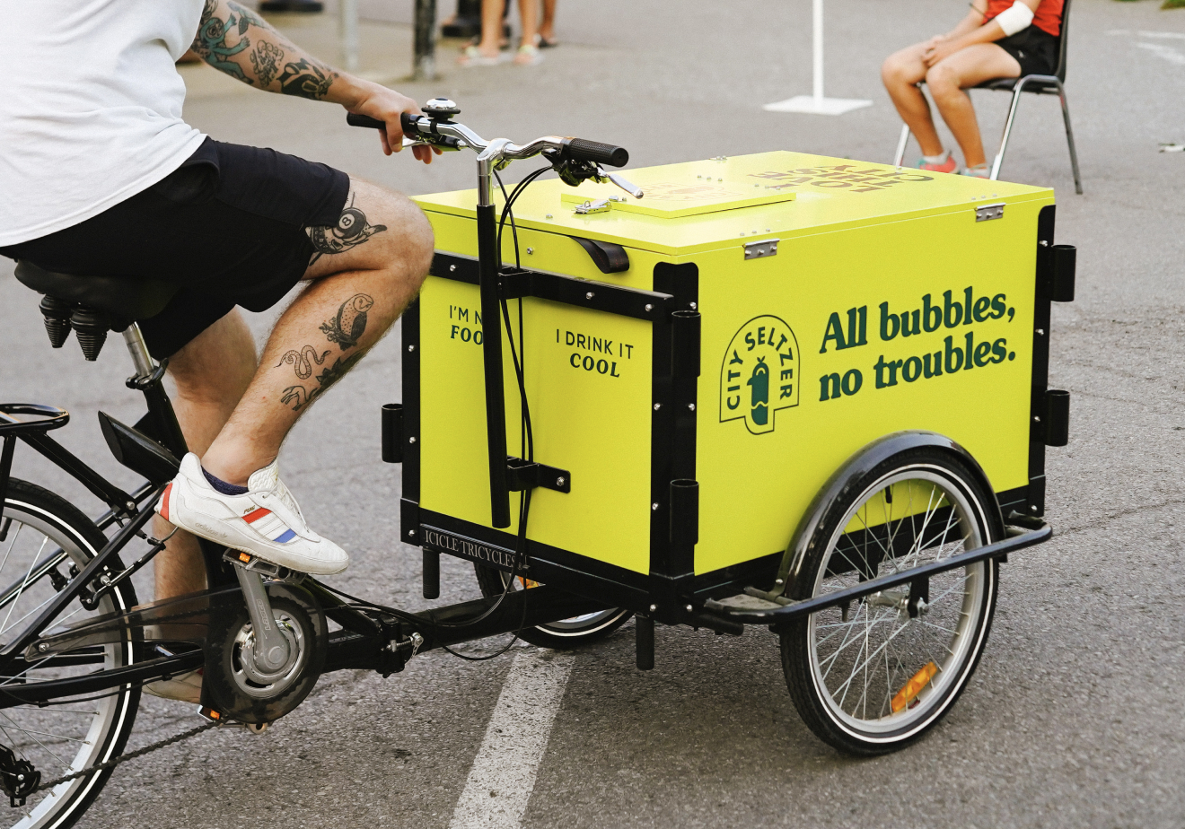 Man riding a City Seltzer branded bicycle cart