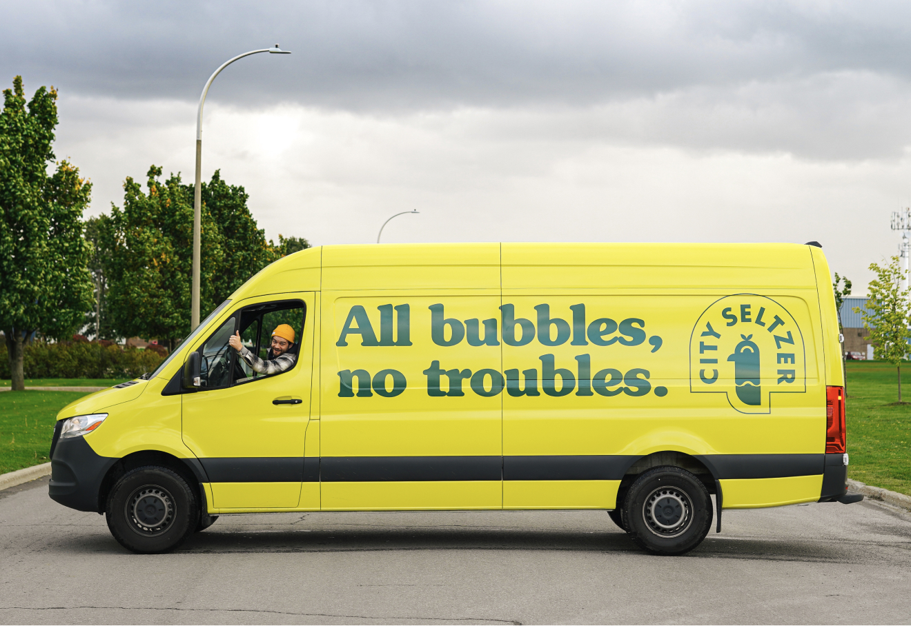 Bright green-on-yellow branded City Seltzer van, featuring the patented "All bubbles no troubles" tagline.