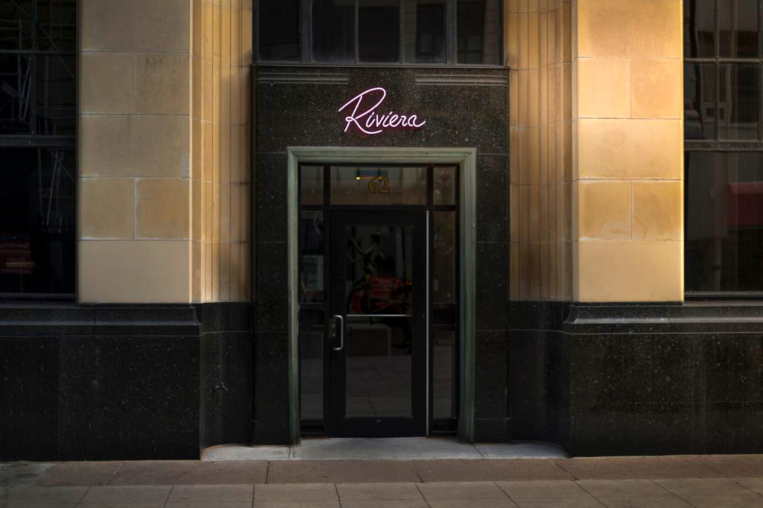 Promo image: Exterior of Riviera with neon logo sign. 