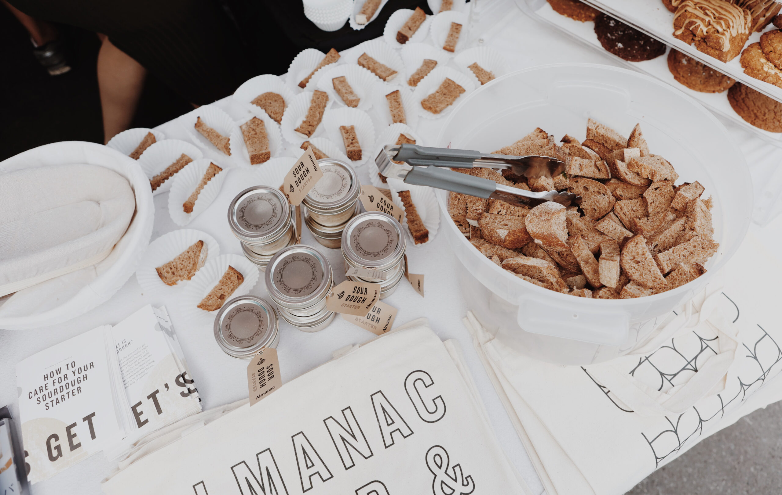 Table with tote bags and jars of sourdough starter